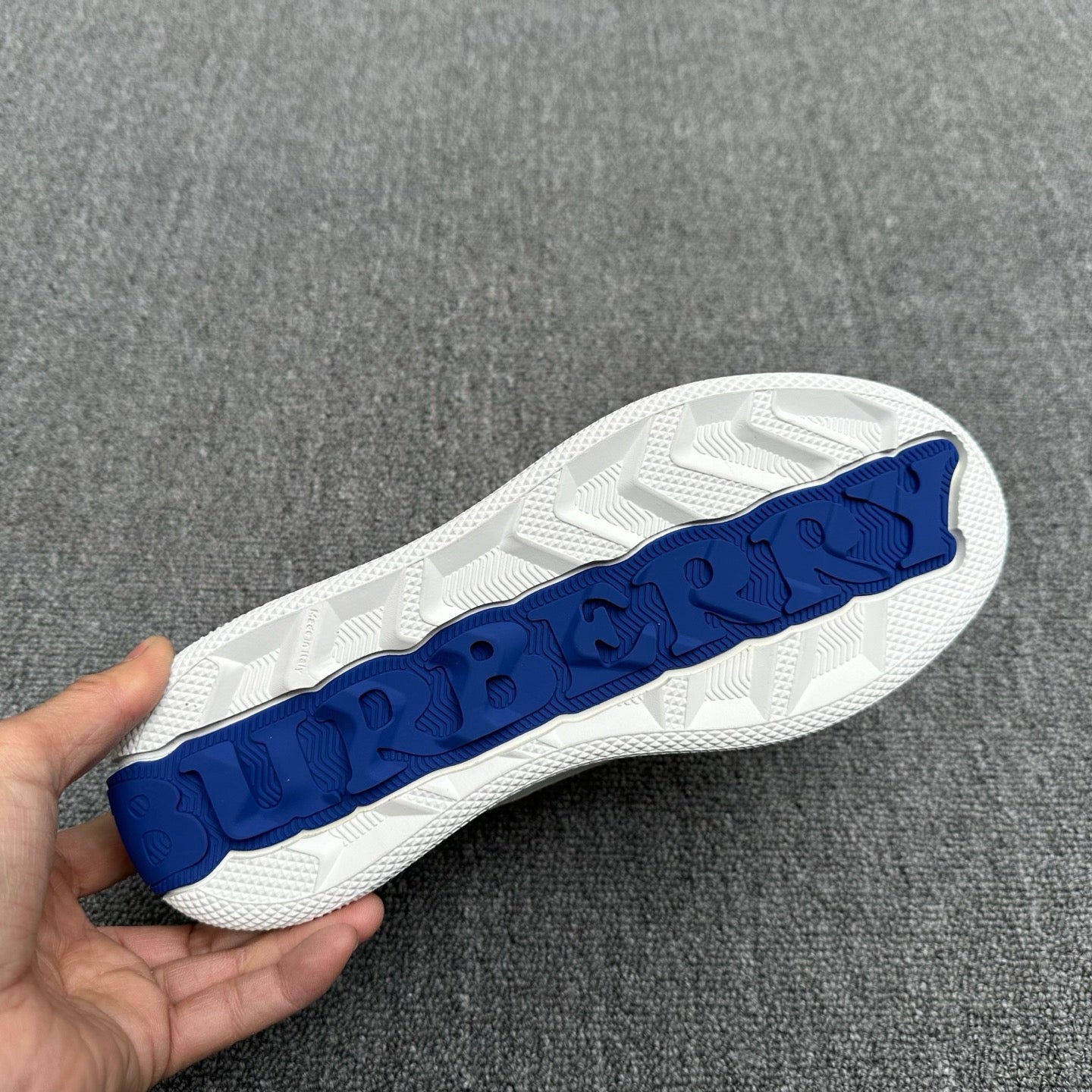 White sneaker outsole with blue textured logo tread