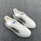 Pair of white sneakers with plaid cutout panels and blue horse logo on tongue