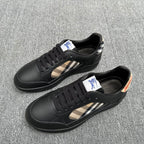 Black low-top sneakers with beige plaid side stripe and blue logo patch
