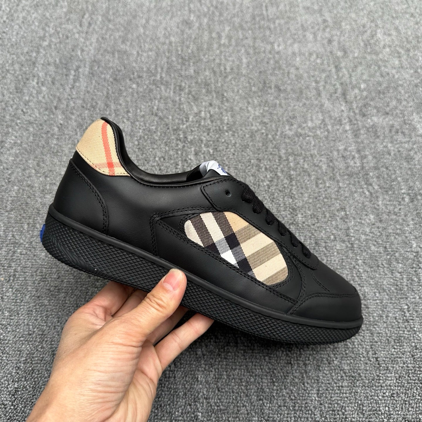 Black sneaker with beige plaid panel, lace-up front, and textured sole