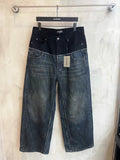 Two-tone denim jeans with dark upper, patchwork panels, and distressed hem at bottom.