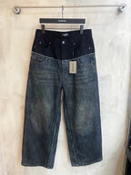 Two-tone denim jeans with dark upper, patchwork panels, and distressed hem at bottom.