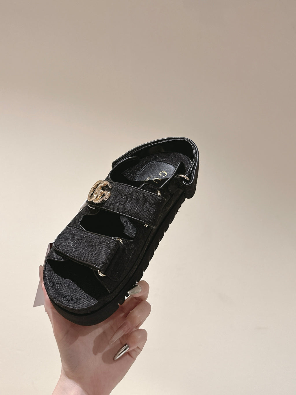 Black Gucci sandals side view with embossed upper and gold-tone GG buckle