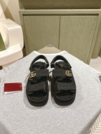 Black Gucci slide sandals with adjustable strap and gold-tone GG buckle
