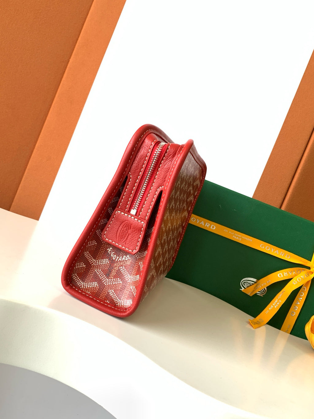 Red Goyard-pattern zip wallet with leather tab and top zipper, side view