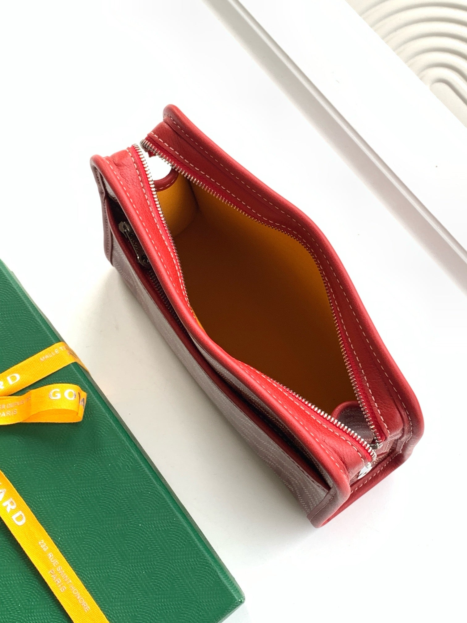 Red zip wallet open, showing brown interior lining and stitched edges