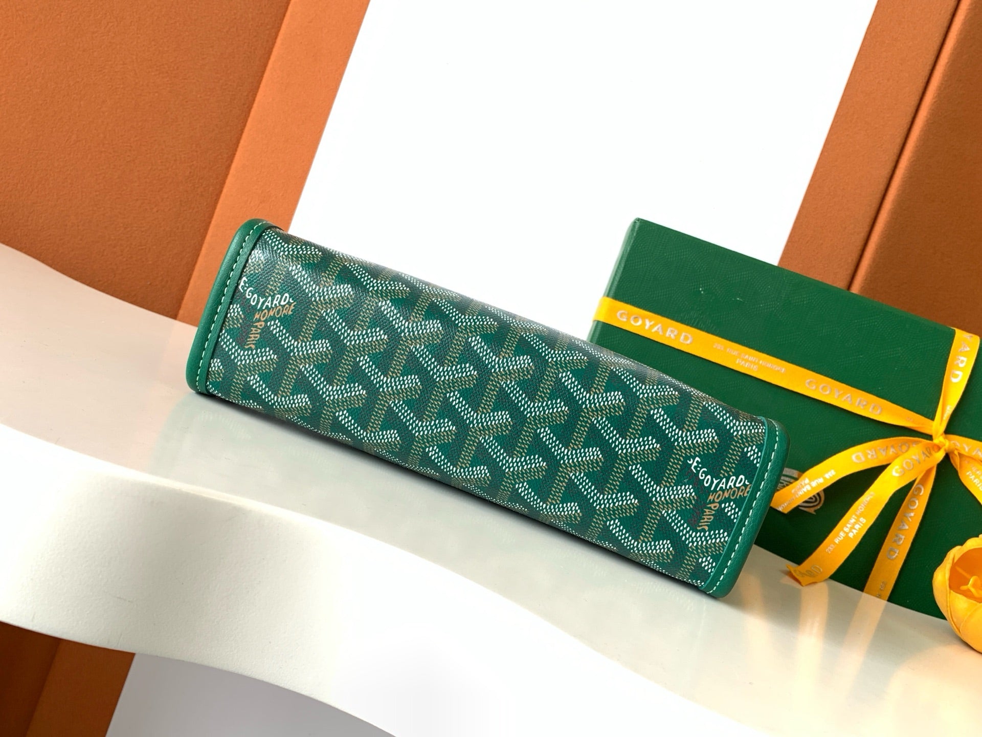 Goyard green patterned zip wallet laid flat, yellow ribbon accents