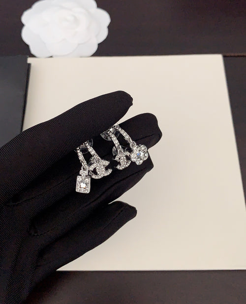 Silver-tone rhinestone Chanel charm earrings on black glove