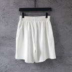 White elastic-waist shorts with a black oval logo on the right leg.
