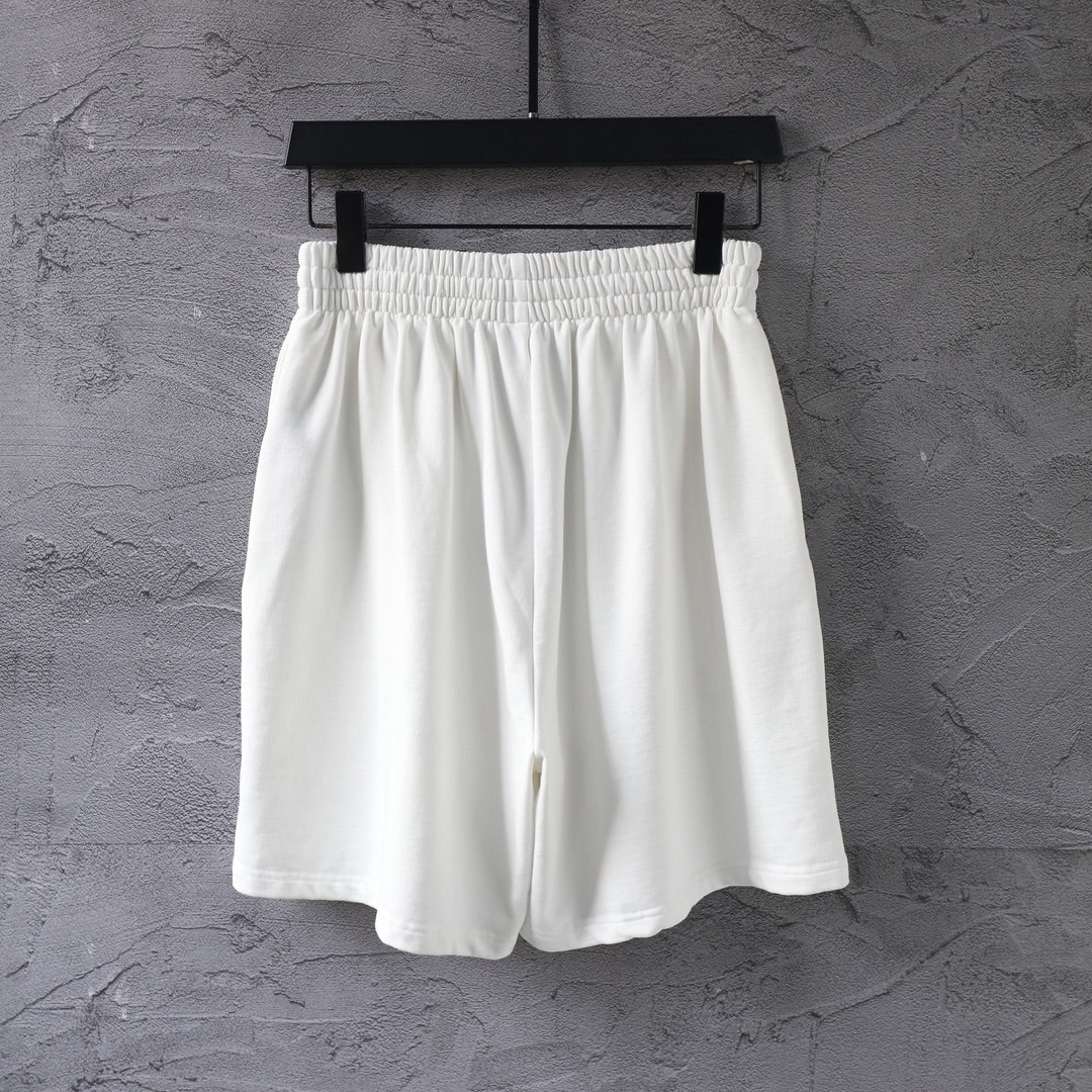 White elastic-waist shorts with a black oval logo on the right leg.
