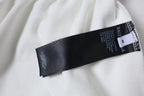 White shorts with black inner size label and brand text on waistband