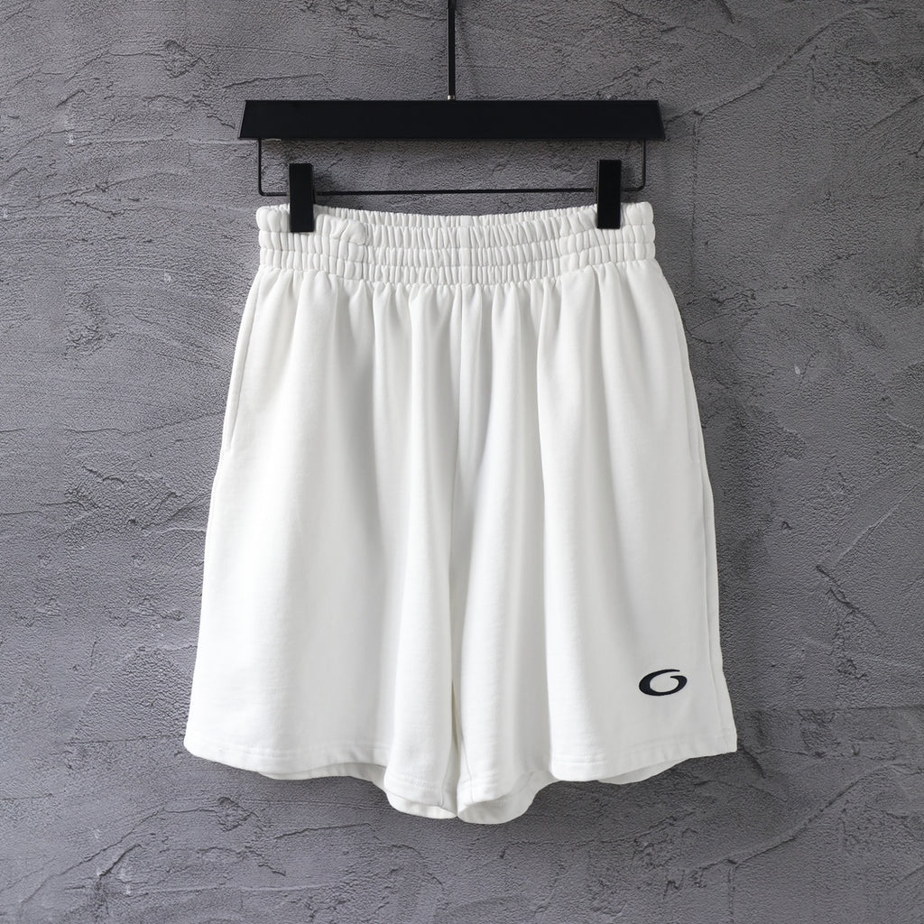 White elastic-waist shorts with black oval logo on the right leg.