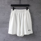 White elastic-waist shorts with black oval logo on the right leg.