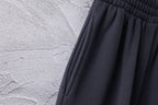 Dark Balenciaga pants fabric with subtle texture and pleated drape