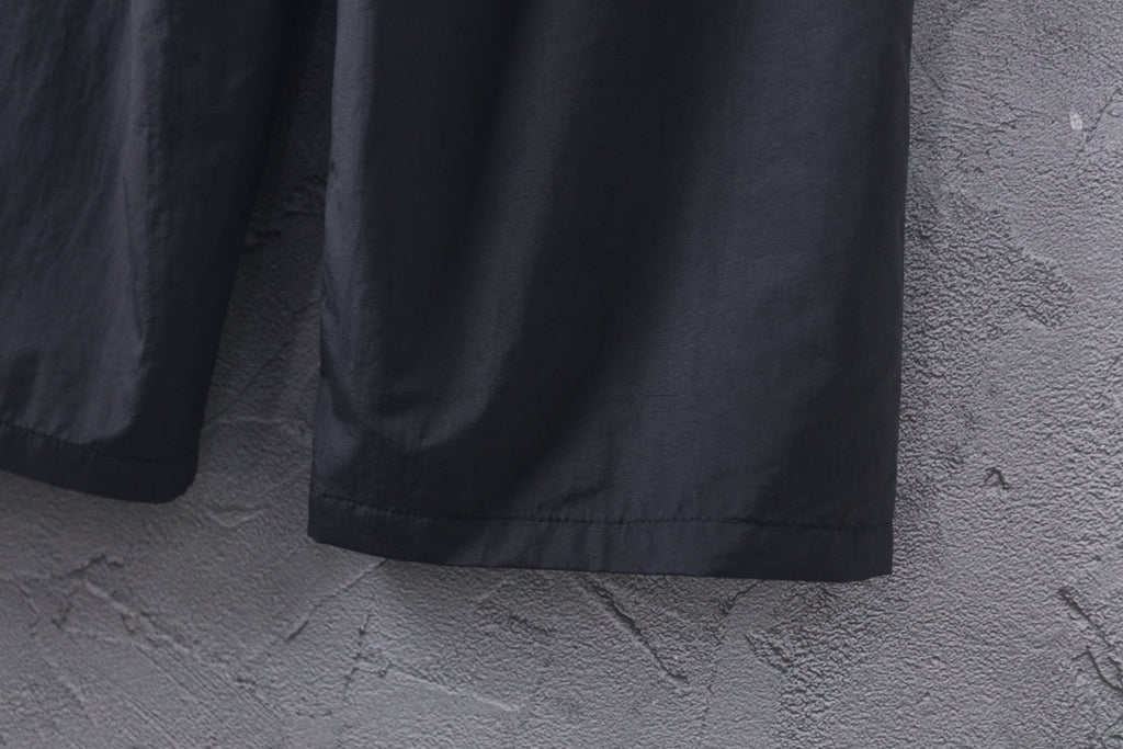 Black wide-leg pants showing straight hem and relaxed drape at bottom