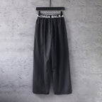 Black wide-leg pants with elastic waistband and large Balenciaga text logo