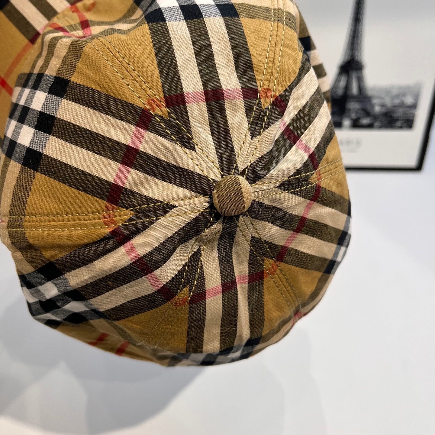 Plaid cap crown close-up with central button and tan/black/red grid fabric