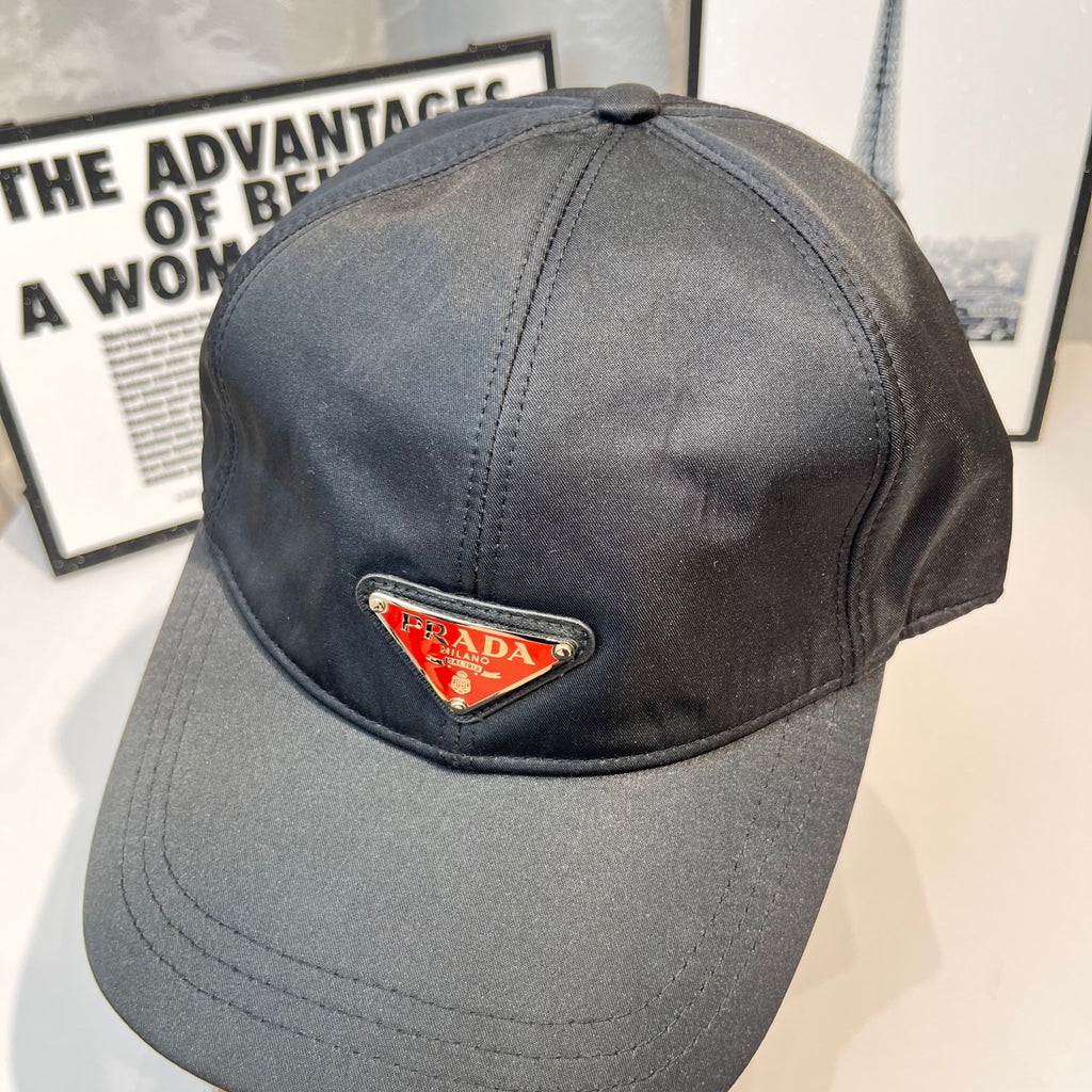 Prada cap in dark gray fabric with triangular logo patch, front close-up.