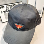 Prada cap in dark gray fabric with triangular logo patch, front close-up.