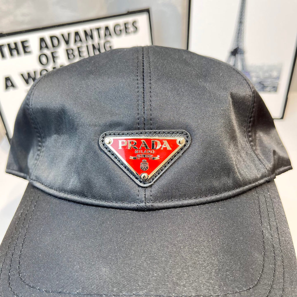 Prada cap in dark gray fabric with triangular logo patch, top close-up.