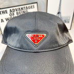 Prada cap in dark gray fabric with triangular logo patch, top close-up.