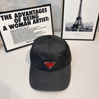 Prada cap in dark fabric with triangular logo patch and curved brim.