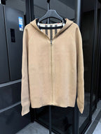 Beige zip-front sweatshirt with raised collar and black-and-white striped inner hood