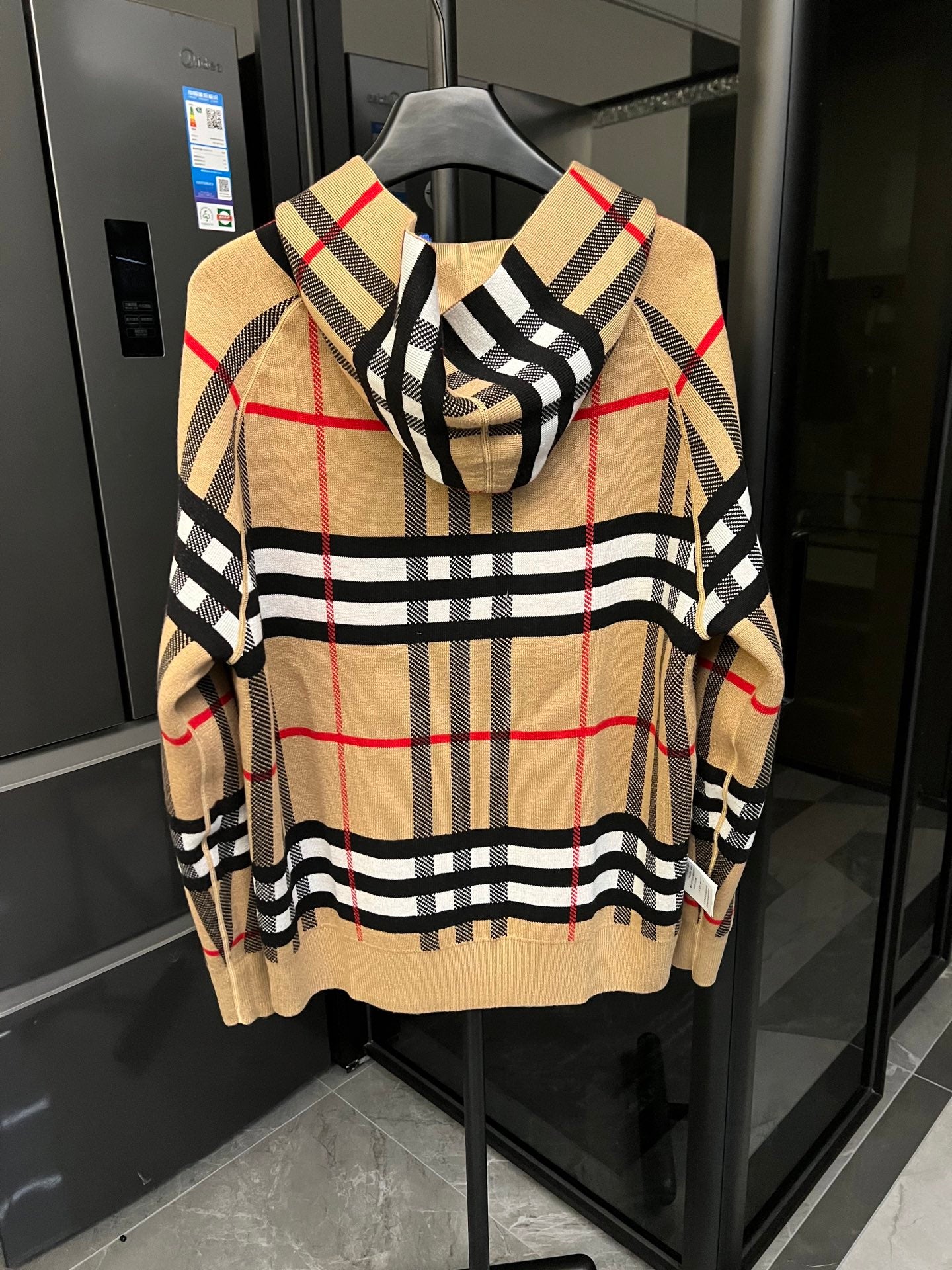 Beige plaid zip-front hoodie with black check stripes and red accents on sleeves