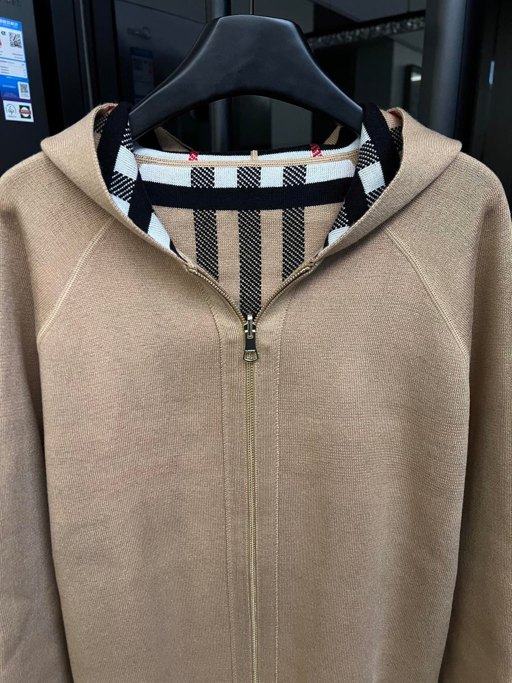 Beige zip-front sweatshirt with stand collar and black-and-white striped inner neck facing