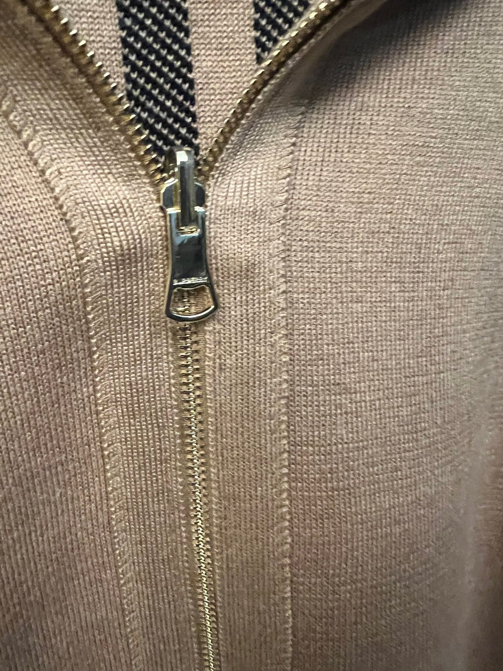 Beige knit sweatshirt front with metal zipper and zipper pull