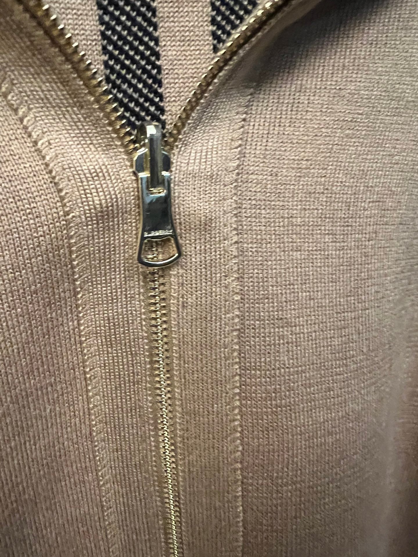 Beige knit sweatshirt front with metal zipper and zipper pull