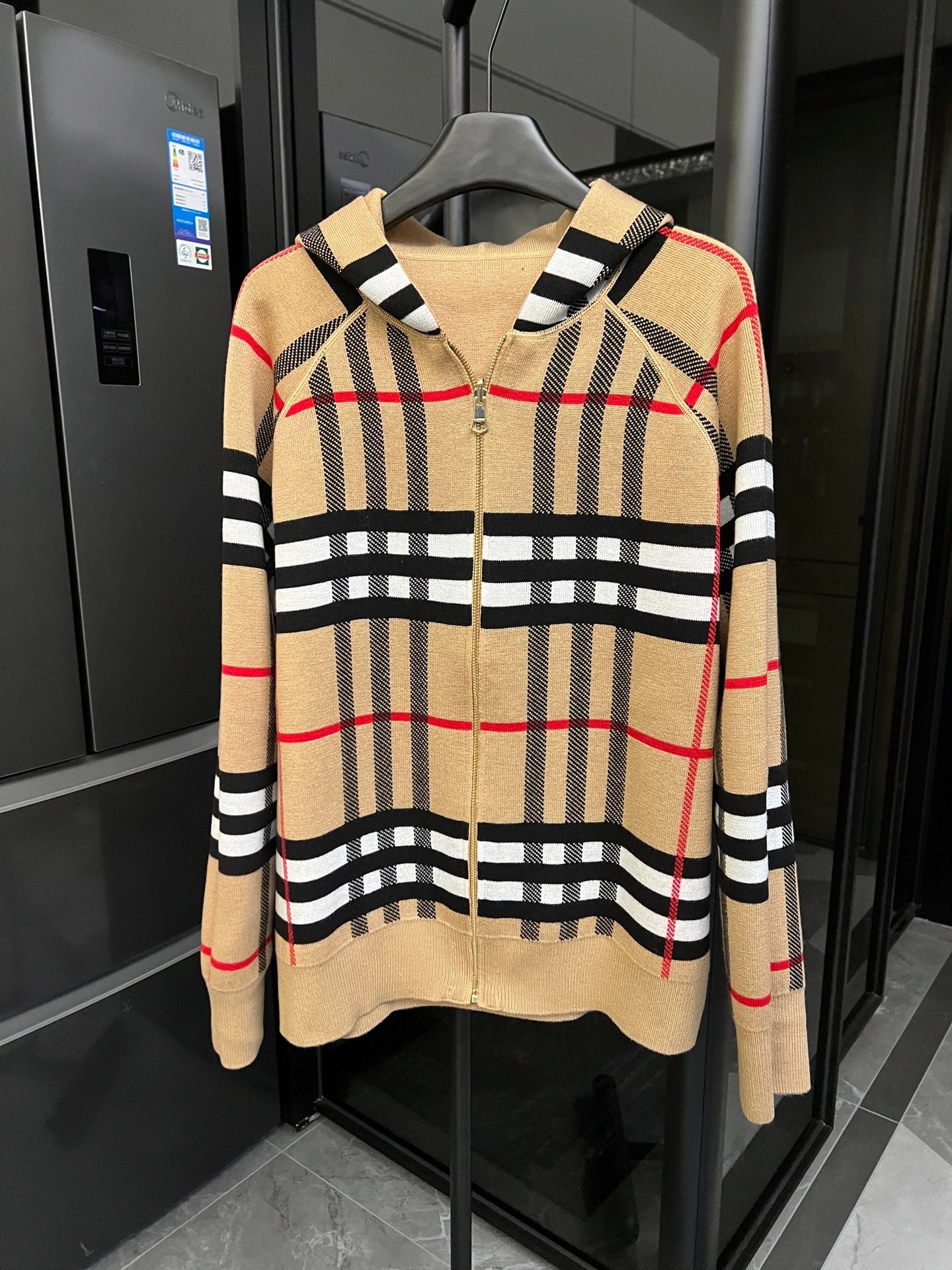 Beige plaid zip-front hoodie with black striped trim and red windowpane lines