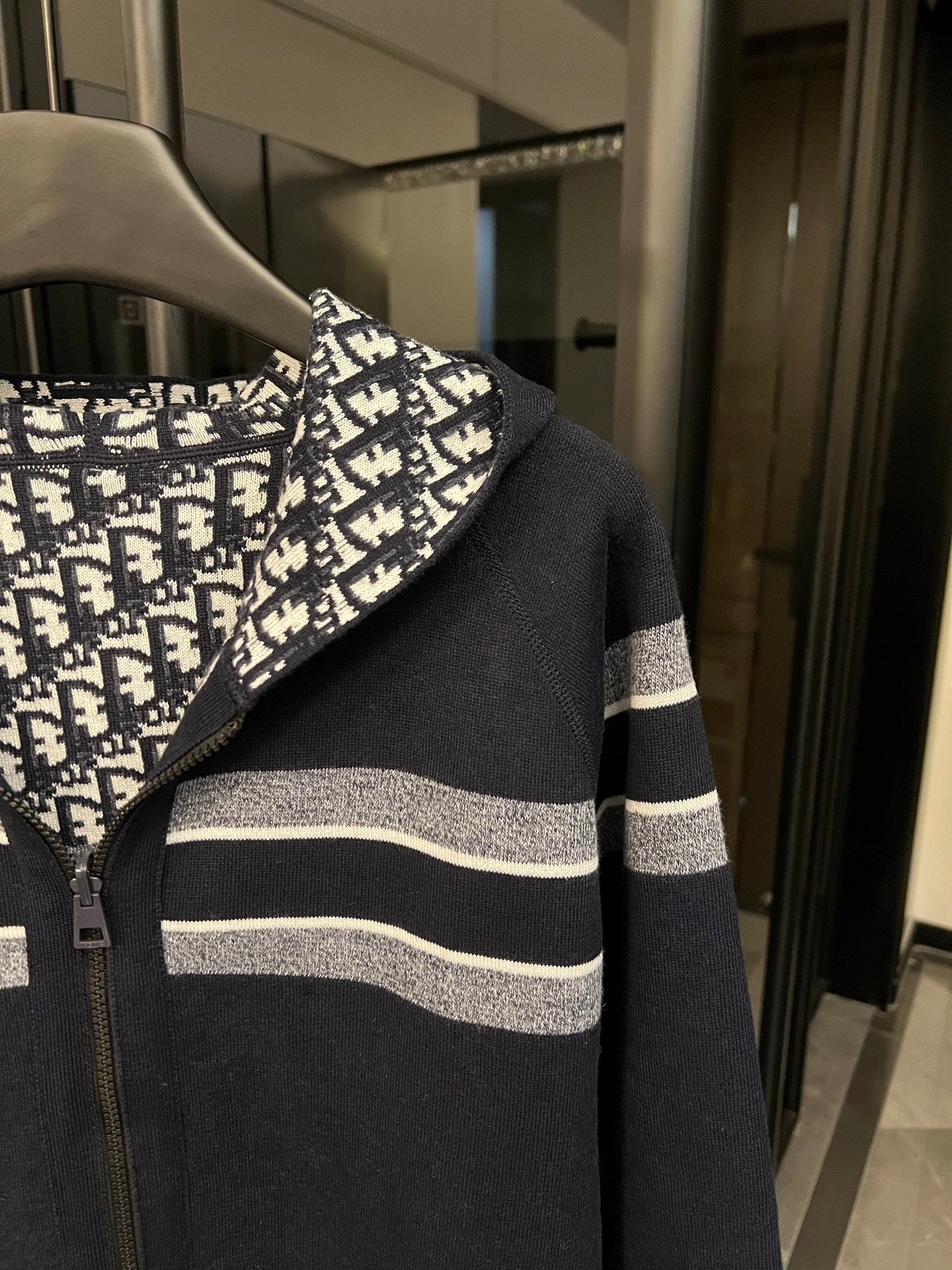 Dior hooded zip jacket side view with logo-print hood and navy-and-white striped sleeves