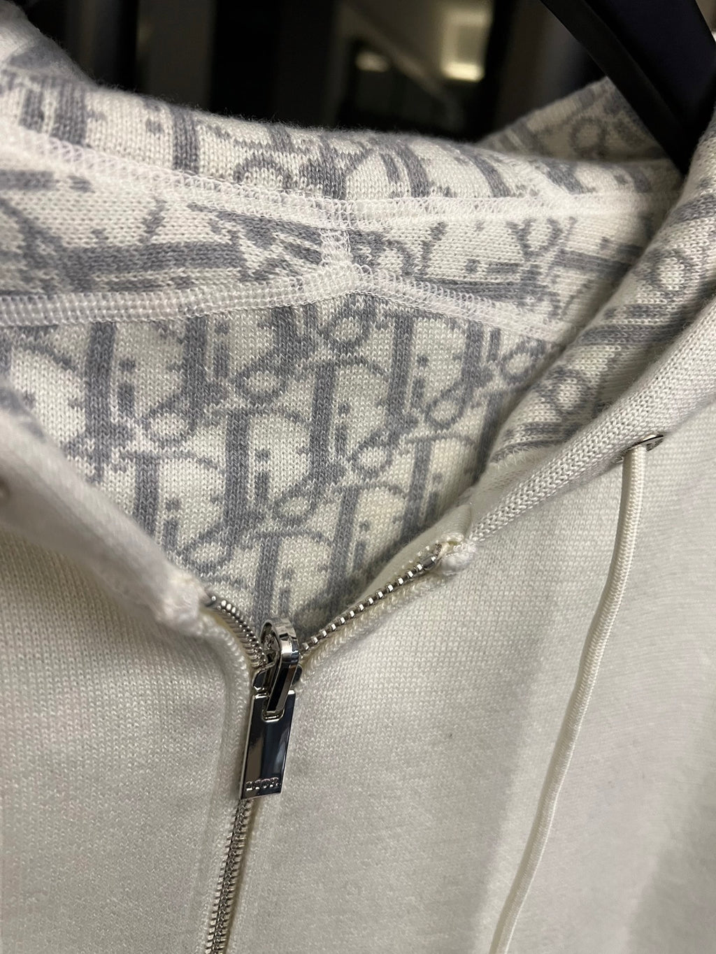 Off-white hoodie front close-up with zipper and patterned hood lining panel.