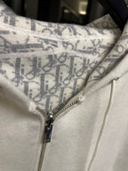 Off-white hoodie front close-up with zipper and patterned hood lining panel.