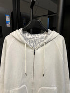Off-white zip-up hoodie with central zipper, drawstring hood, and patterned lining.