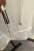 Off-white hoodie pocket and drawstring cords close-up with knit hem detail.