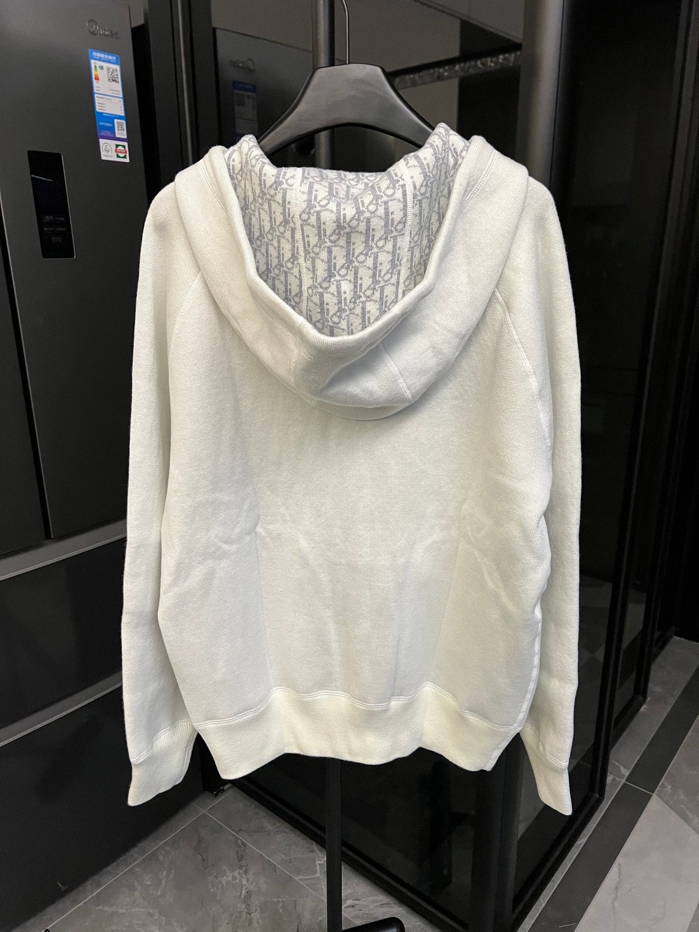 Off-white zip-up hoodie back view with patterned hood lining and long sleeves.