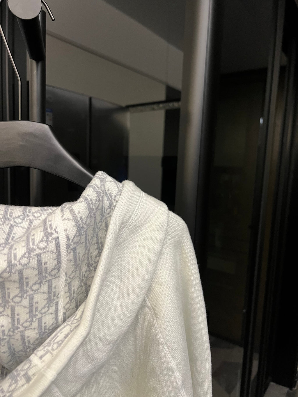 Off-white hoodie shoulder with patterned inner hood lining and drawstring cords.