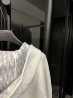 Off-white hoodie shoulder with patterned inner hood lining and drawstring cords.