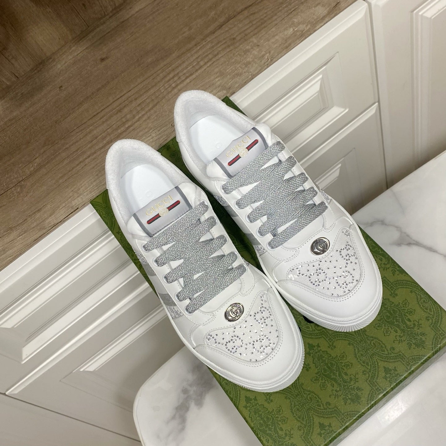 Pair of white Gucci unisex sneakers with gray lace and perforated toe design