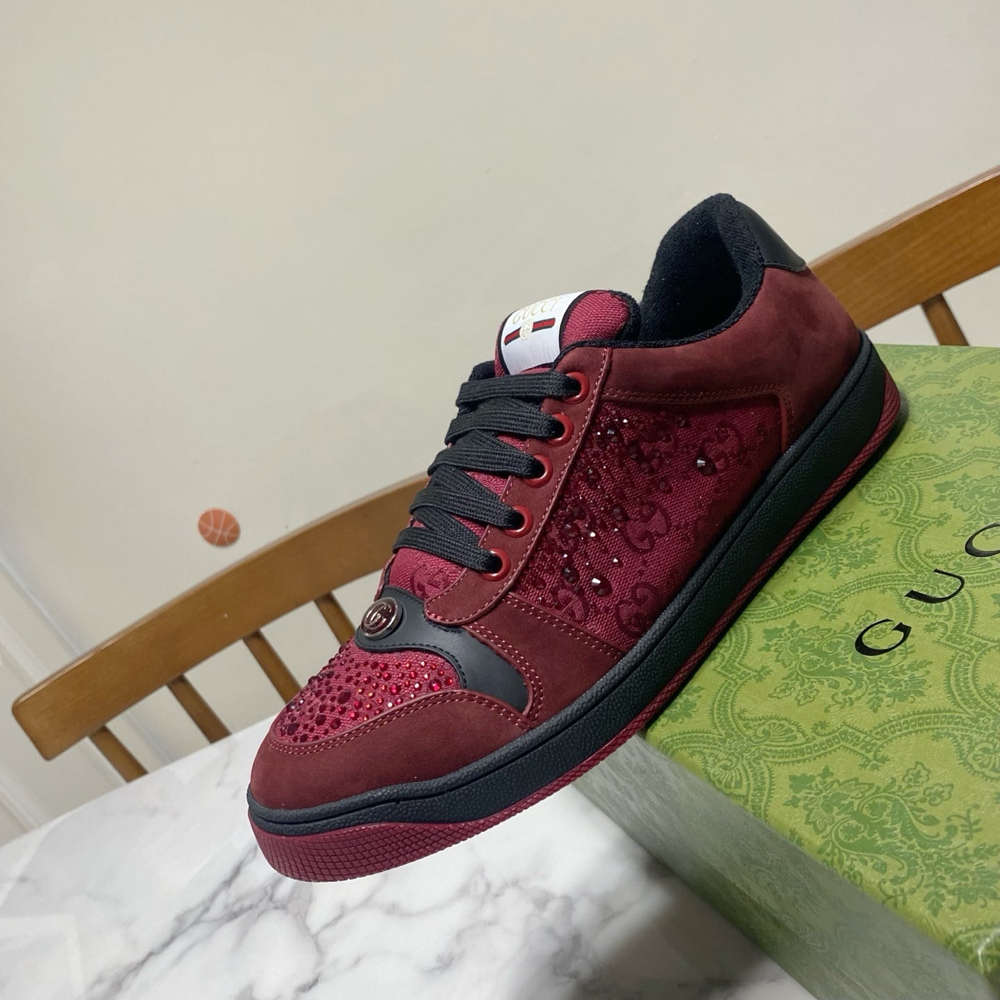 Gucci unisex sneakers angled view, burgundy leather with black laces and side logo patch