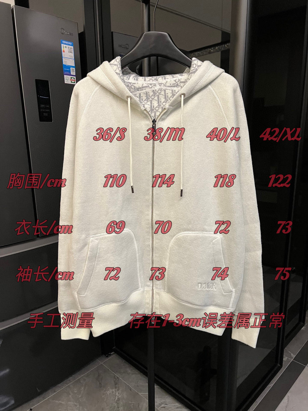 Off-white zip-up hoodie with hood, drawstring ties, and front pockets on display.