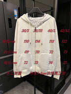 Off-white zip-up hoodie with hood, drawstring ties, and front pockets on display.