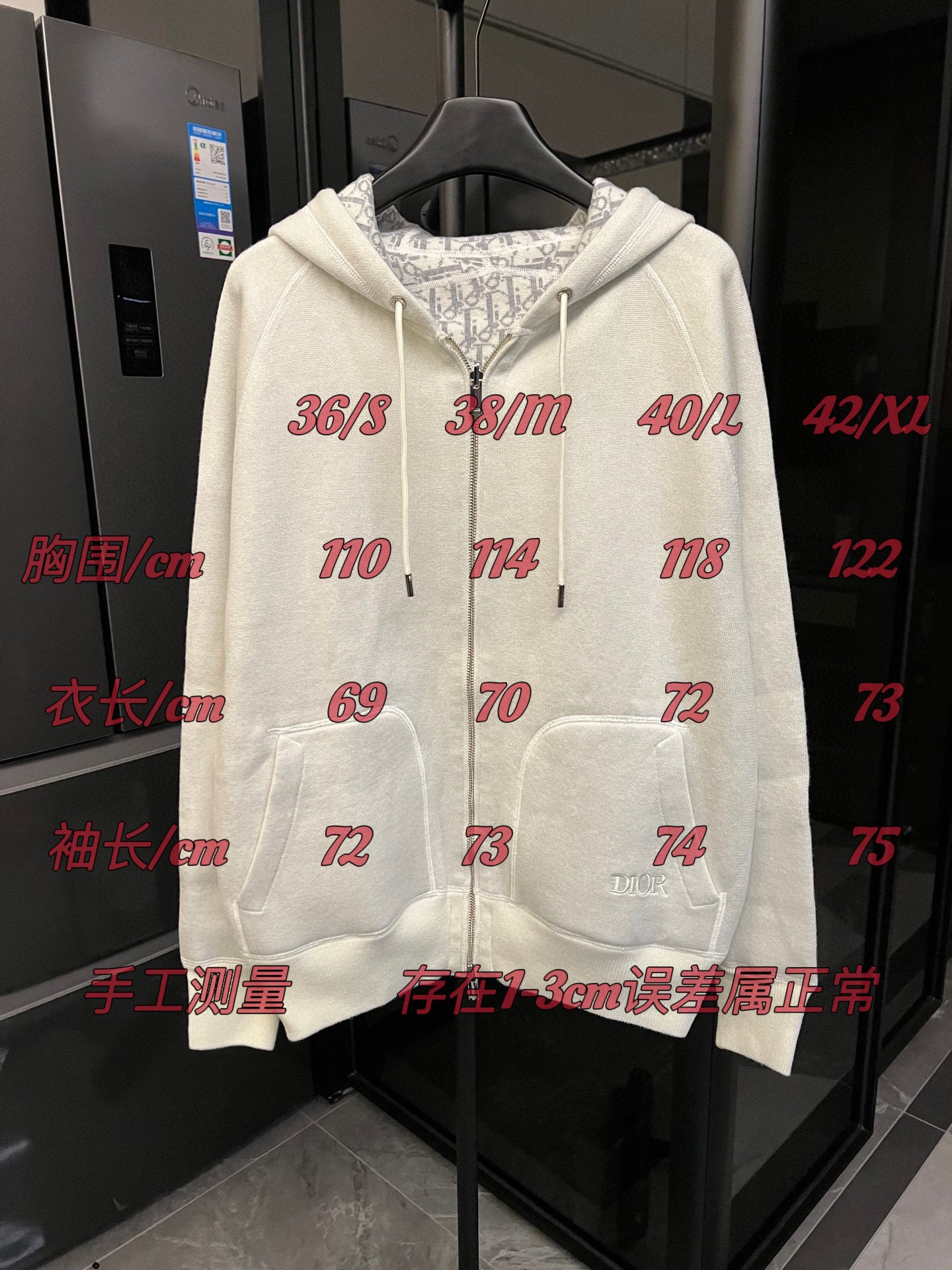 Off-white zip-up hoodie with hood, drawstring ties, and front pockets on display.