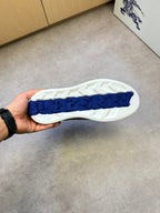 White treaded outsole with blue logo patch on black-and-check sneaker sole