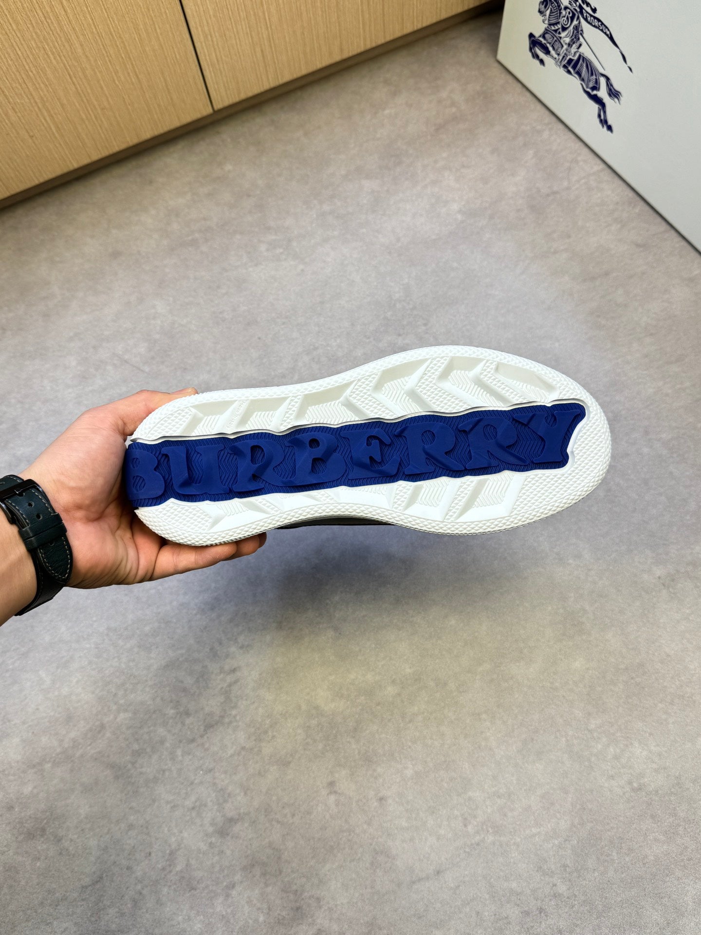 White treaded outsole with blue logo patch on black-and-check sneaker sole