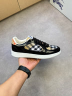 Black and white checkered sneakers in hand, showing black laces and white sole