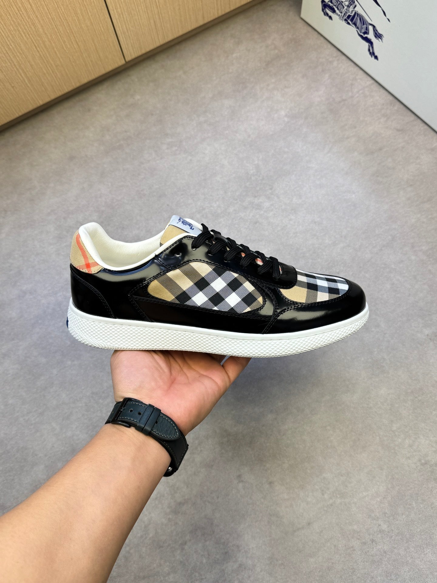 Black and white checkered sneakers in hand, showing black laces and white sole