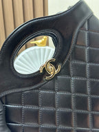 Black quilted handbag close-up of gold-tone ring logo clasp